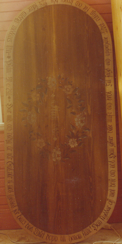 7 Det
                        här är en bordsskiva som är laserad i grönumbra.
                        Den är dekorerad med en krans av blommor och en
                        vers runt om.